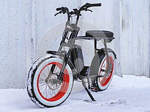 Black powerful electric fat bike in a snowy yard