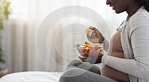 Black Pregnant Lady Enjoying Fresh Vegetable Salat While Sitting On Bed