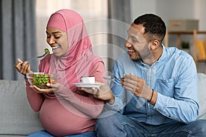 Black Pregnant Muslim Woman Eating Vegetable Salad While Husband Offering Her Cake