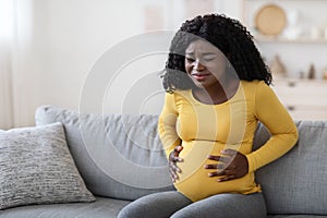 Black pregnant woman suffering from labor pains at home