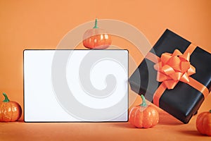 Black present box with orange ribbon and pumpkin and empty blank lightbox on orange background. Happy halloween