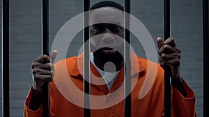 Black prisoner holding bars and looking at camera, drug dealer punishment photo