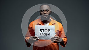 Black prisoner holding stop racism sign, psychological abuse, ill treatment