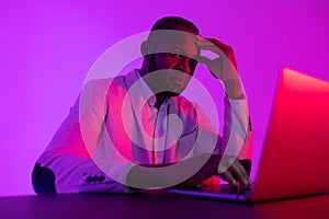 A black programmer works using a laptop computer. the man works at night.