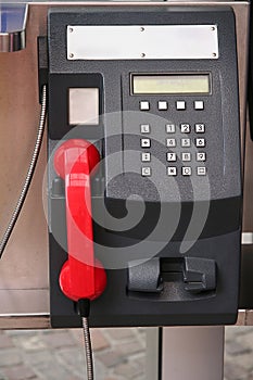 Black public phone with red receiver