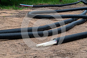 Black PVC electric pipes with wires on the ground. Construction site, power line with cable wires