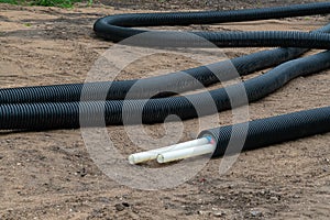 Black PVC electric pipes with wires on the ground. Construction site, power line with cable wires