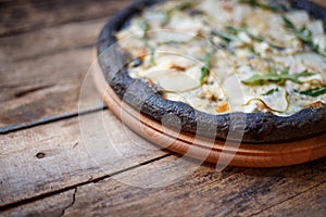 Black quattro formaggi pizza on wooden background