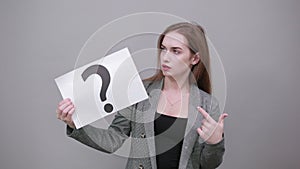 Black question mark on a piece of white paper. Close-up hand holding symbol