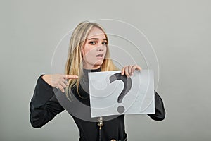 Black question mark on a piece of white paper. Close-up hand holding symbol