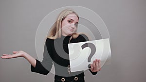 Black question mark on a piece of white paper. Close-up hand holding symbol