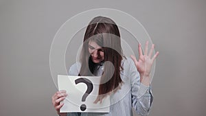 Black question mark on a piece of white paper. Close-up hand holding symbol