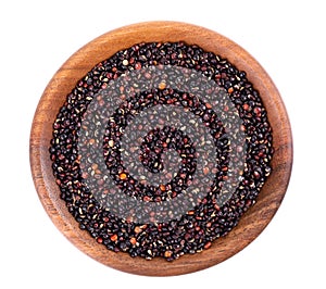 Black quinoa seeds in wooden bowl, isolated on white background. Pile of raw kinwa. Top view.