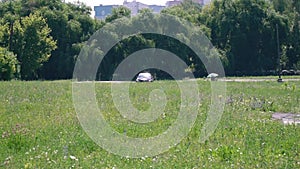 Black racing car in stickers rides on the road among grass and electronic towers