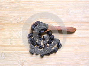Black raisin on wooden spoon