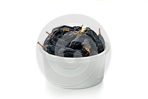 Black raisins in cup on white background