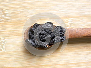 Black raisins on wooden spoon