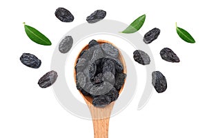 black raisins in wooden spoon with green leaves isolated on white background. top view