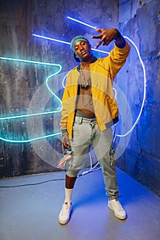 Black rapper in underpass neon light on background