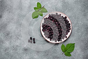 Black raspberries in a bowl on a gray concrete background. View from above, flat lying