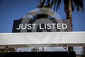 A black realtor sign with white letters advertising a new home listing