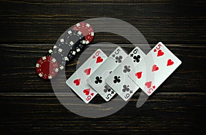 Black and red chips and playing cards with a winning combination of two pairs on a dark vintage table. Low key concept of winning