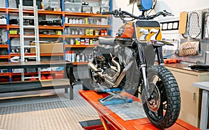 Black and red custom motorcycle over platform ready to check on empty workshop