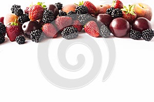 Black and red food. Ripe blackberries, strawberries, plums and peaches on white background. Berries at border of image with copy s