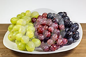 Black, red, green seedless grapes in a deep white bowl