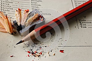 BLACK AND RED SHARPENED PENCIL WITH SHRPENER AND WOOD SHAVINGS