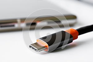 Black and red USB Type-C connector next to a modern mobile phone on a light background. Shallow depth of field. Selective focus. photo