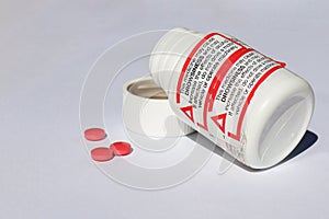 Black, red and white Medicine May Cause Drowsiness warning label on pill bottle and red pills