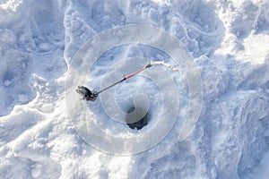 A black reel and gold rod for ice fishing.
