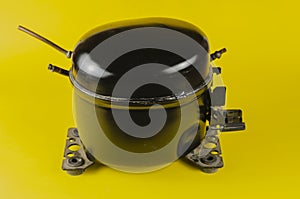 Black Motor-Compressor of the refrigerator on a yellow background