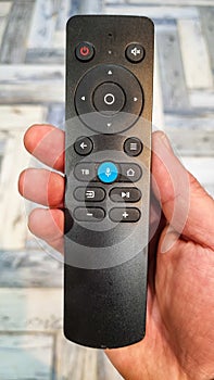 Black remote control for a set-top box in a man& x27;s hand.