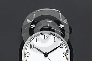 Black retro alarm clock on gray dark background top view Flat lay copy space. Minimalistic background, concept of time, deadline,