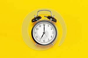 Black retro alarm clock on yellow background top view Flat lay copy space. Minimalistic background, concept of time, deadline,