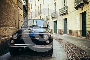 Black retro car parked on narrow italy street in Sardinia island