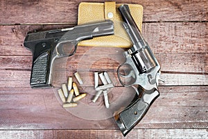 Black revolver gun and Semi-automatic 9mm gun on wooden background
