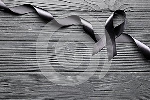Black ribbon on a black wooden background. Mourning. Sorrow.