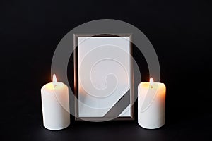 Black ribbon on photo frame and candles at funeral