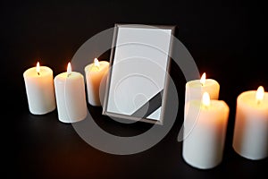 Black ribbon on photo frame and candles at funeral