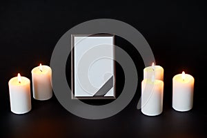 Black ribbon on photo frame and candles at funeral