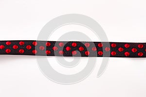 Black ribbon with red polka dot pattern.