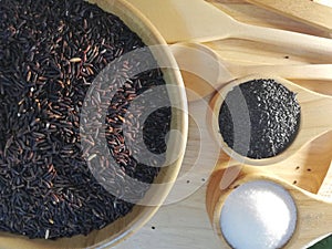 Black rice, black sesame, sugar, in a wooden dish, placed on a wooden tray.