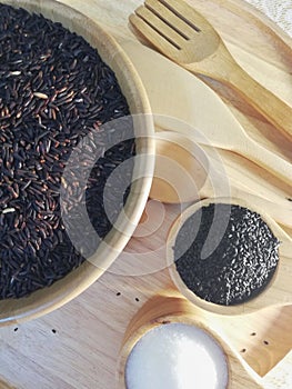 Black rice, black sesame, sugar, in a wooden dish, placed on a wooden tray.