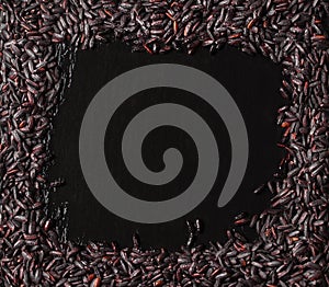 Black rice in frame on a dark stone background with water droplets