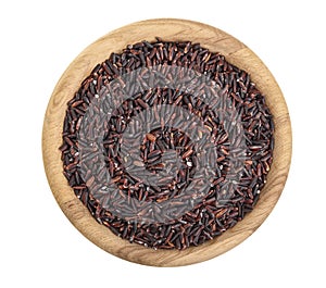 Black rice grains in wooden bowl isolated on white background. Top view. Flat lay