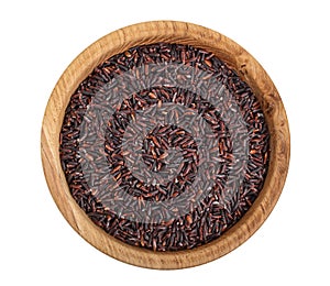 Black rice grains in wooden bowl isolated on white background. Top view. Flat lay