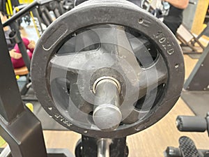 A 10 kg black weight plate is mounted on a gym machine.